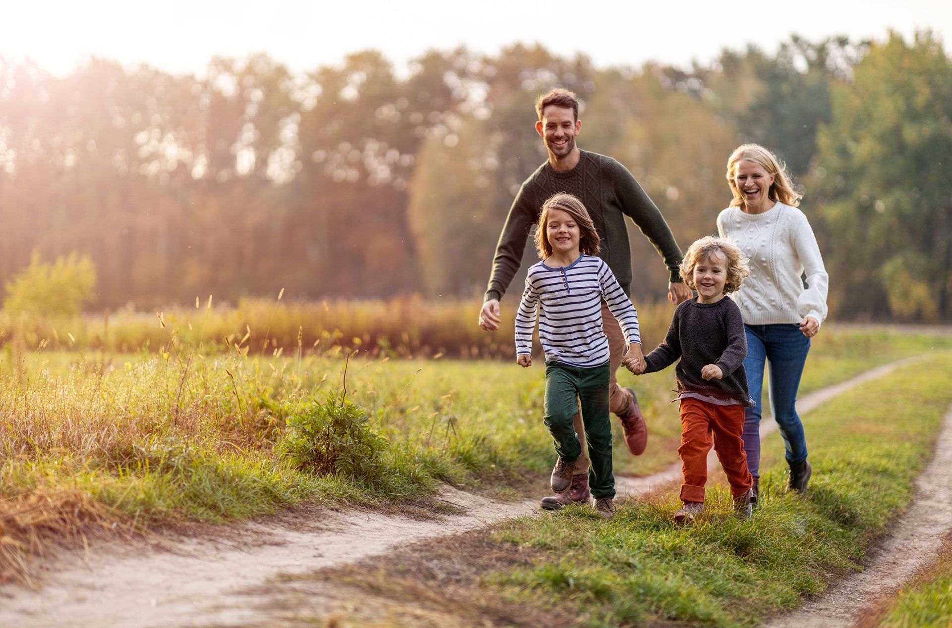Parents and two children walking in a parklike setting