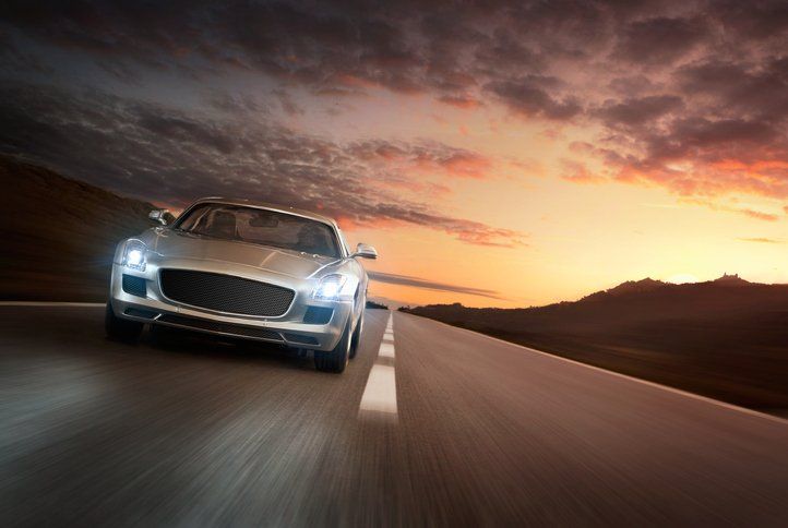 Sports car driving on a road at dusk